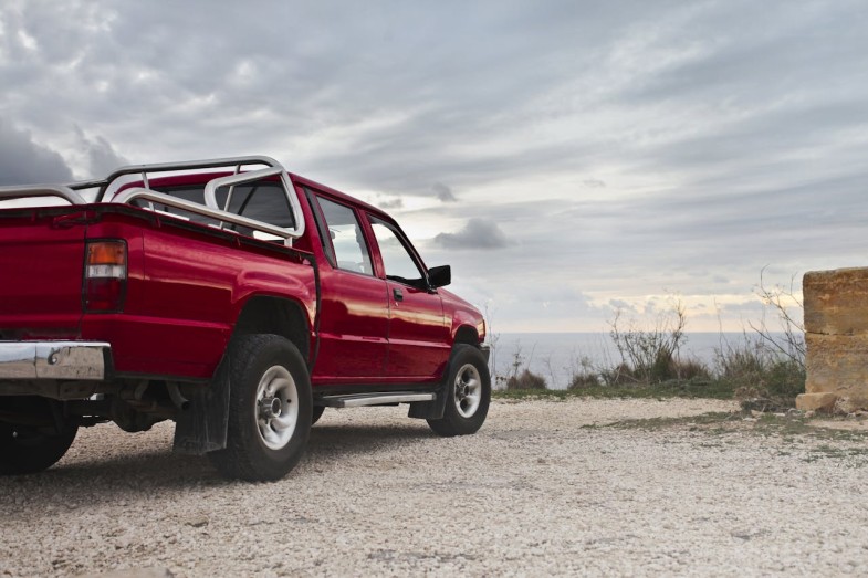 RED PICK UP TRUCK PARKED NEAR WALL