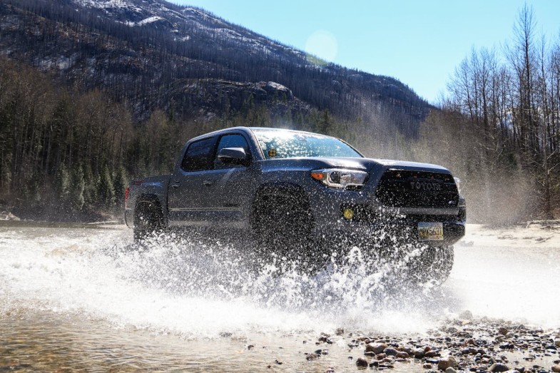 TOYOTA TACOMA DRIVING THROUGH PUDDLE ON DIRT ROAD