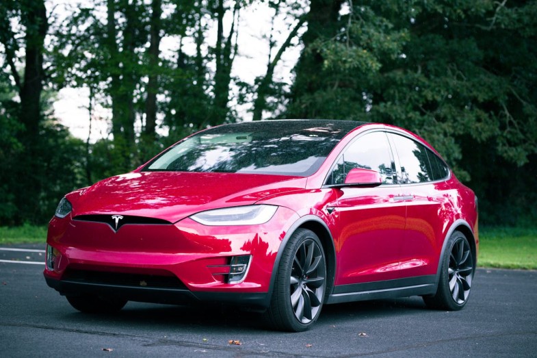 TESLA RED CAR PARKED ON ASPHALT ROAD