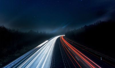 LIGHT TRAILS ON HIGHWAY AT NIGHT