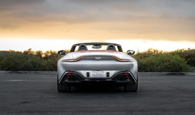 GRAY ASTON MARTIN ON THE ROAD DURING SUNSET