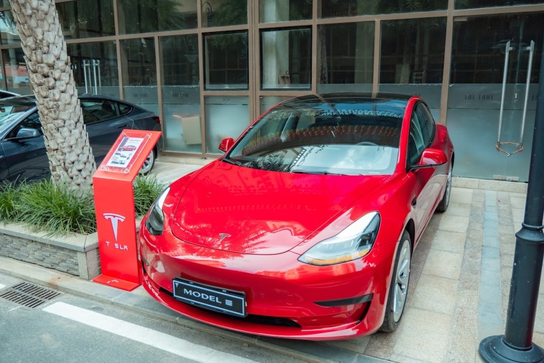 RED TESLA CAR PARKED OUTSIDE A BUILDING