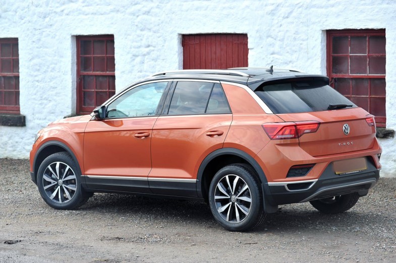 ORANGE SUV PARKED BESIDE WHITE CONCRETE BUILDING VOLKSWAGEN