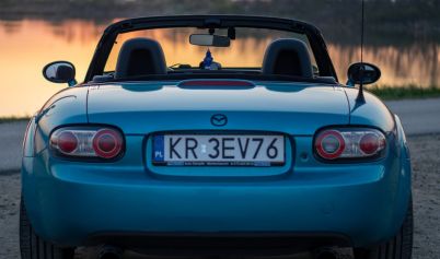 BACK OF BLUE MAZDA MX 5 AT SUNSET