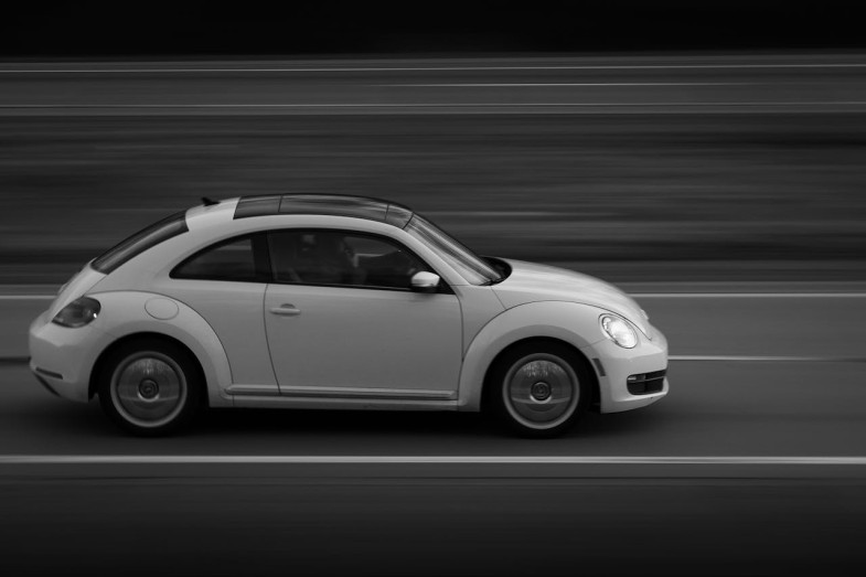 VOLKSWAGEN NEW BEETLE SPEEDING DOWN THE ROAD