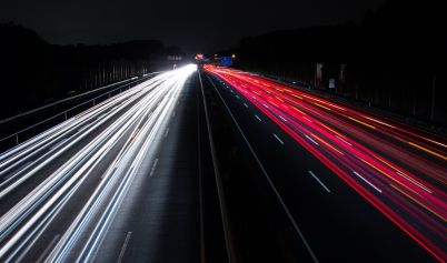 LIGHT TRAILS ON HIGHWAY AT NIGHT