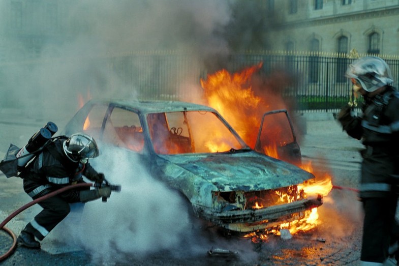 FIRE FIGHTHERS EXTINGUISHING A BURNING CAR