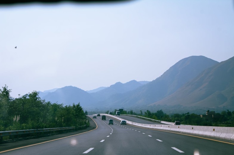 WIDE HIGHWAY NEAR MOUNTAINS ON FOGGY DAY