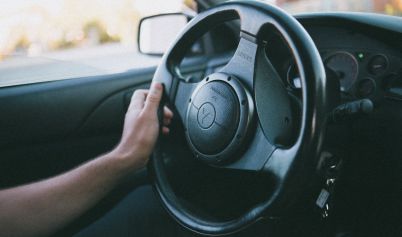 PERSON HOLDING A BLACK MITSUBISHI MOTORS STEERING WHEEL