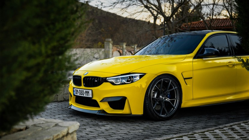 Yellow BMW M3 parked on cobblestone driveway
