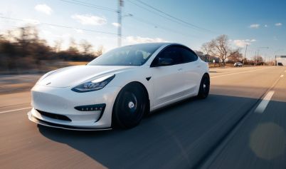 WHITE TESLA DRIVING ON THE ROAD