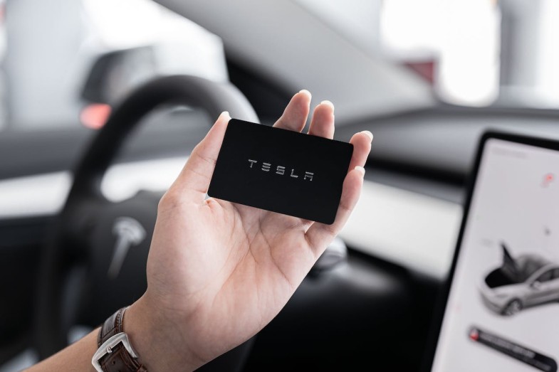 A PERSON HOLDING A TESLA BLACK CARD