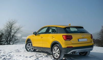 A YELLOW AUDI CAR PARKED ON A SNOW COVERED GROUND