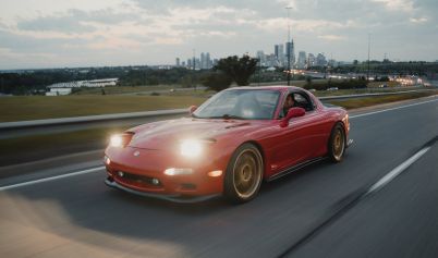 RED CAR DRIVING ON ASPHALT ROAD