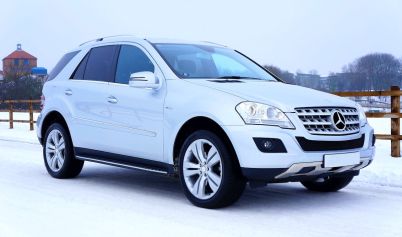 WHITE MERCEDES-BENZ SUV PARKED BESIDE BROWN WOODEN FENCE