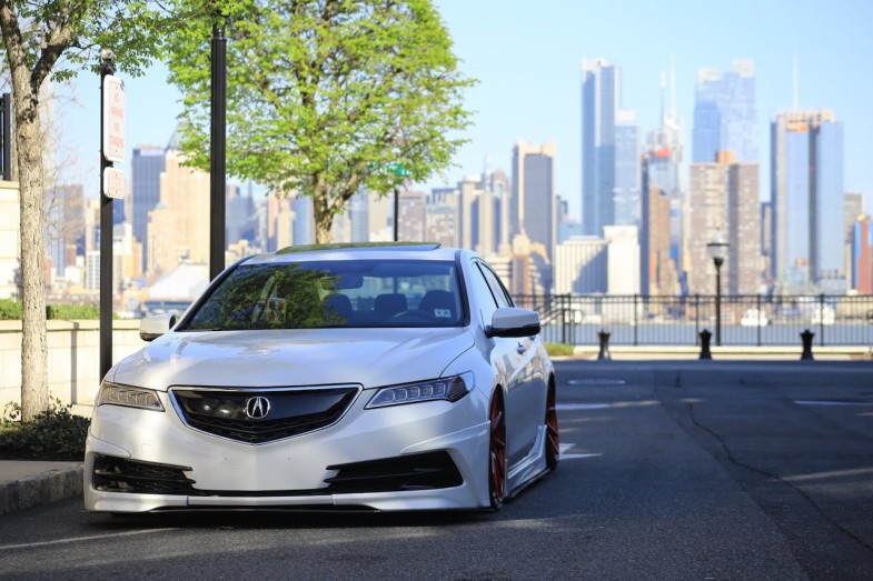 WHITE ACURA SEDAN ON GRAY ASPHALT ROAD NEAR GREEN TREE AT DAYTIME