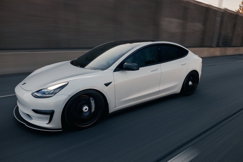 A WHITE TESLA CAR ON A ROAD