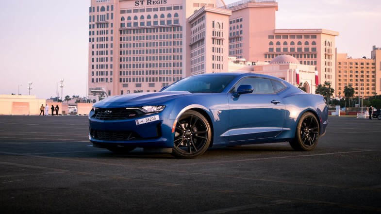 BLUE CHEVROLET SPORTS CAR PARKED ON THE ROAD NEAR CITY BUILDINGS