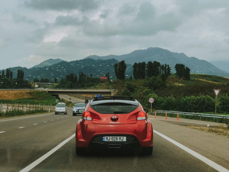 RED CAR DRIVING DOWN THE HIGHWAY