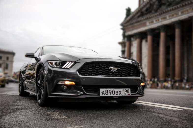 BLACK FORD MUSTANG PARKED ON ASPHALT ROAD