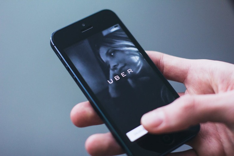 PERSON HOLDING SMARTPHONE WITH UBER LOGO
